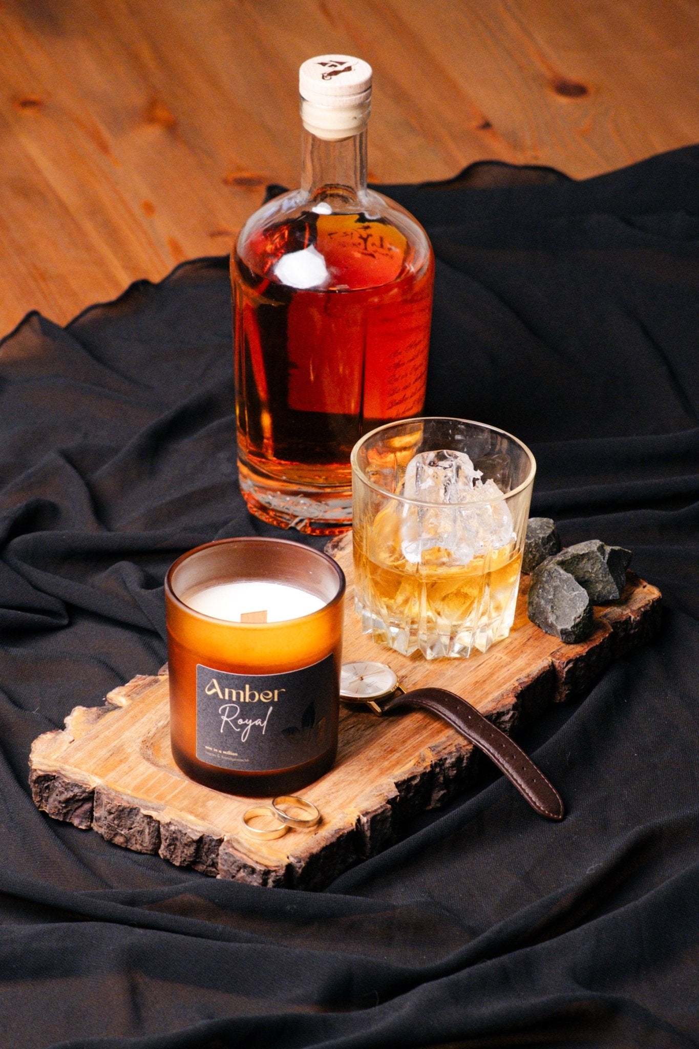 herzton Amber Royal auf Holzscheibe mit Whisky-Glas, Flasche und schwarzem Stoff als Dekoration