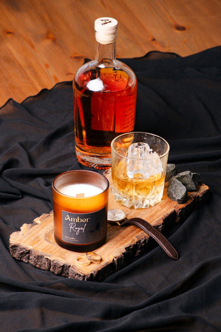 herzton Amber Royal auf Holzscheibe mit Whisky-Glas, Flasche und schwarzem Stoff als Dekoration