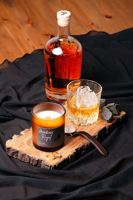 herzton Amber Royal auf Holzscheibe mit Whisky-Glas, Flasche und schwarzem Stoff als Dekoration