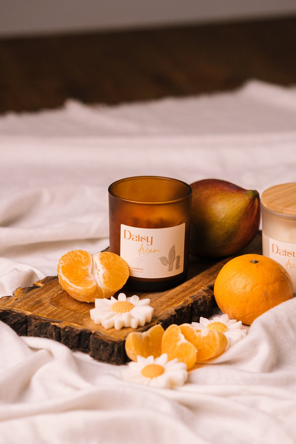 herzton Daisy Dream im Amber-Glas auf Holzscheibe mit frischen Mandarinen und Mango