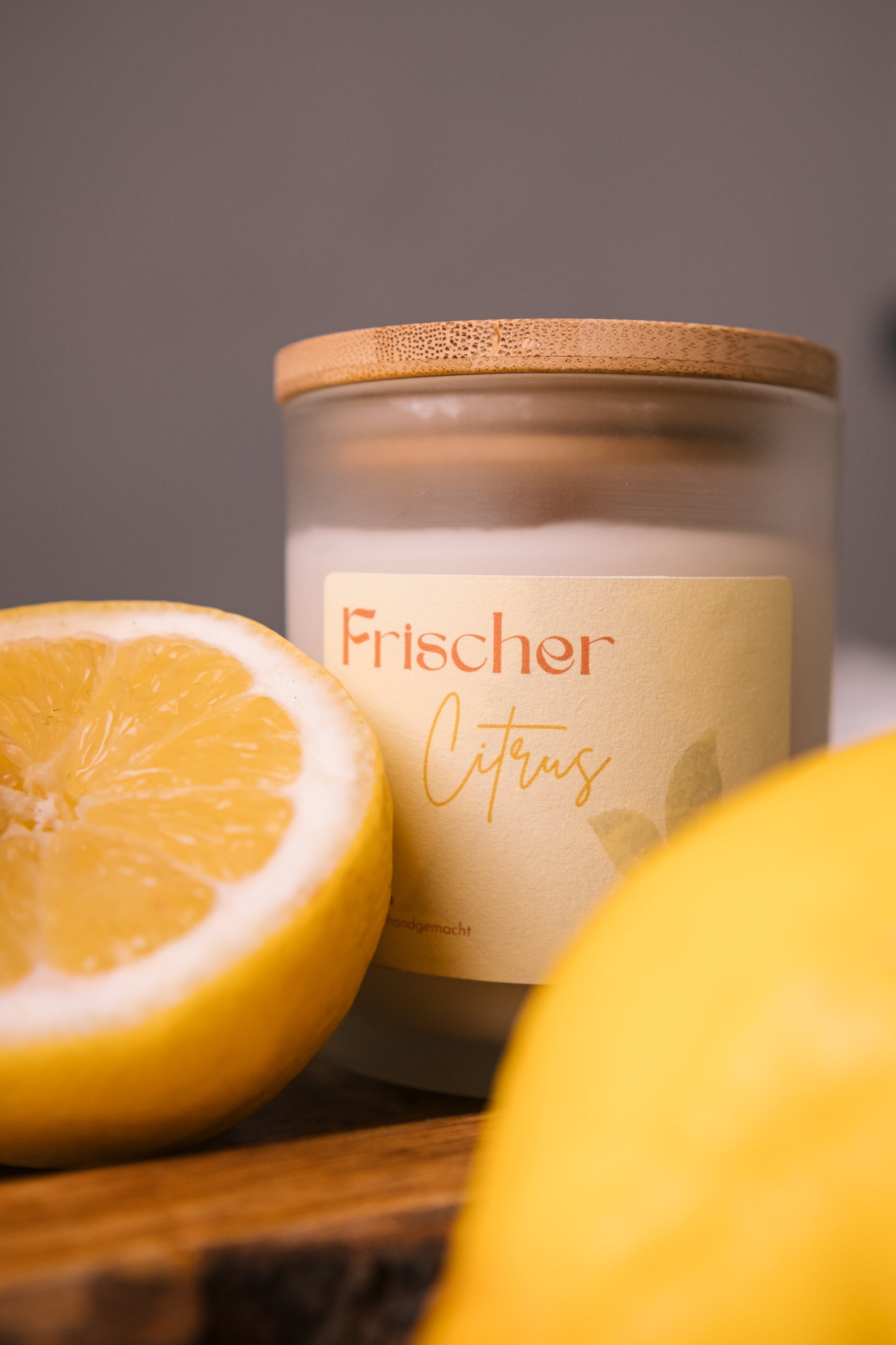 herzton Frischer Citrus auf Holztisch mit Zitronen-Hälften und weiterer Kerze