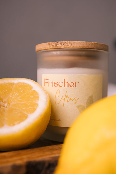 herzton Frischer Citrus auf Holztisch mit Zitronen-Hälften und weiterer Kerze