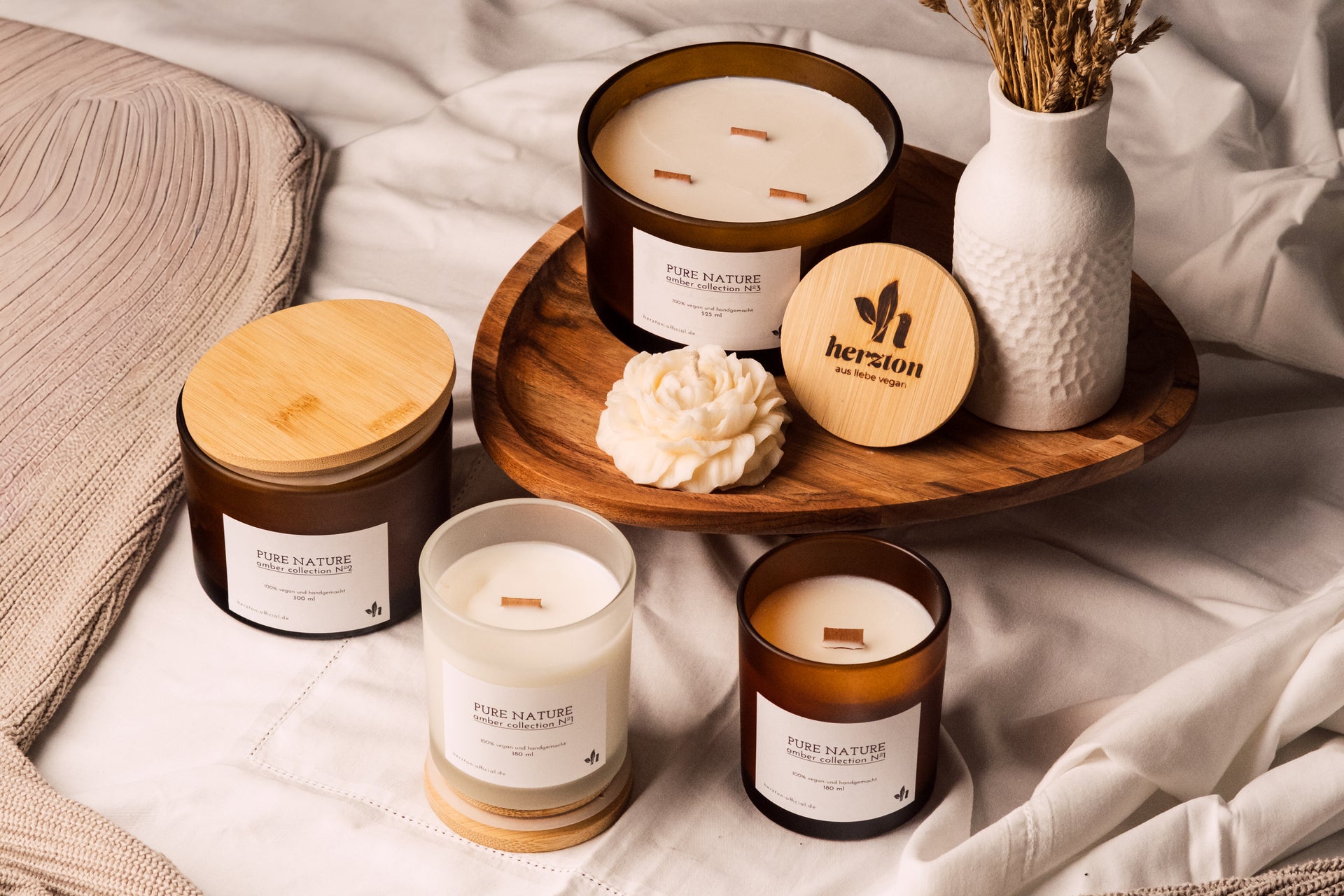 herzton Pure Nature Sojawachskerzen in Braunglas und Klarglas auf Holztablett, Bambus-Deckel und Holzdochte sichtbar