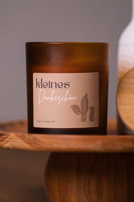 herzton Kerze Kleines Dankeschön im bernsteinfarbenen Glas mit warmem Label auf Holzsockel