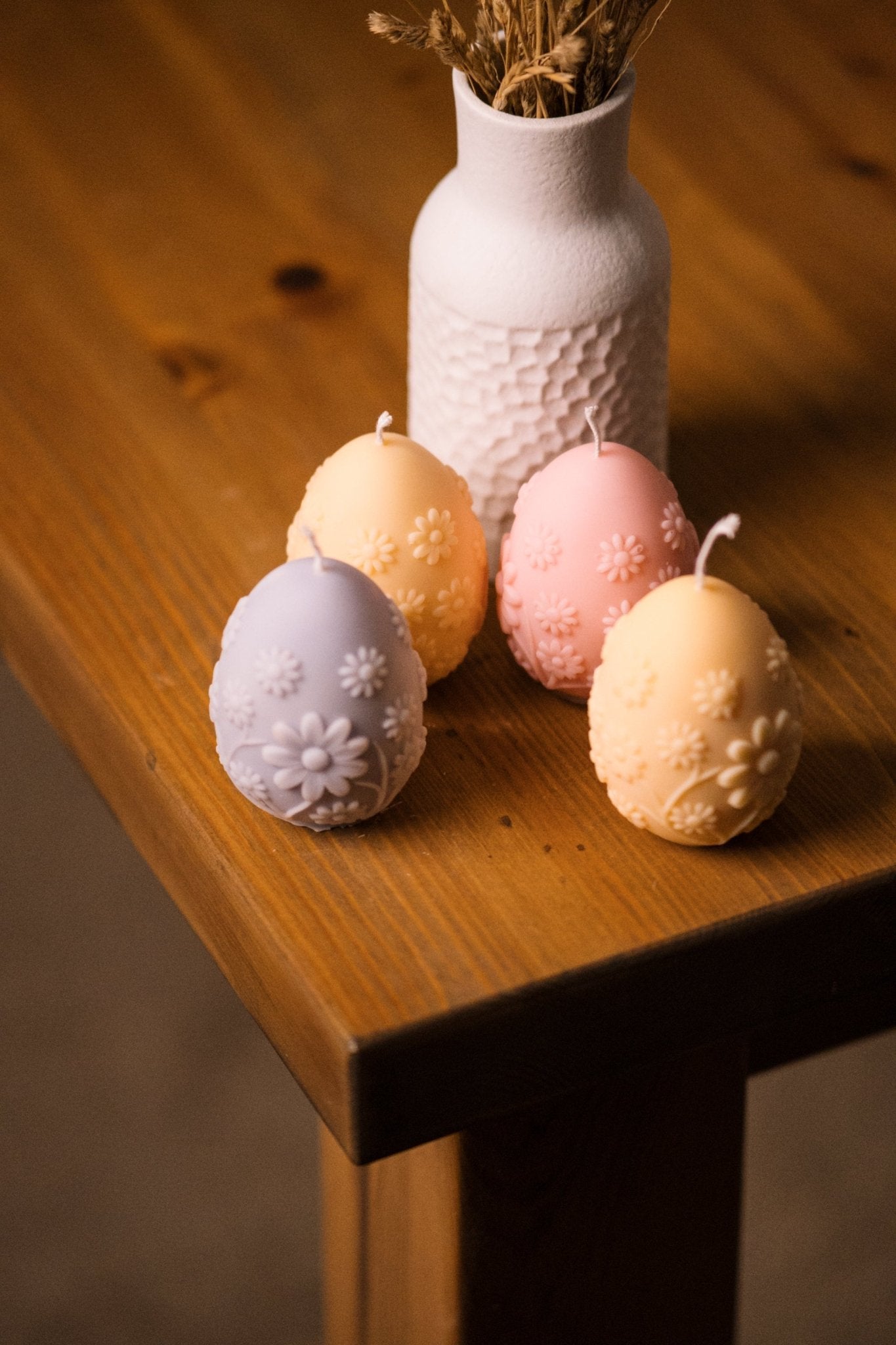 herzton Osterei vier Stück in Lila, Gelb, Rosa und Apricot mit Blütenrelief auf Holztisch