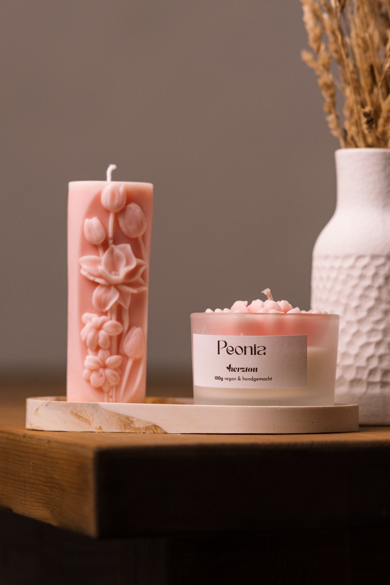 herzton Peonia-Set Draufsicht, rosa Reliefkerze und Pfingstrosenkerze im Glas auf marmoriertem Tablett