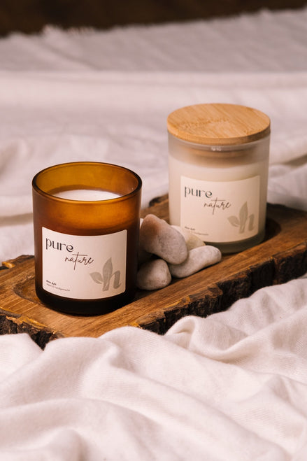 herzton Pure Nature im Bernsteinglas und weißem Milchglas nebeneinander, auf Holz mit Natursteinen