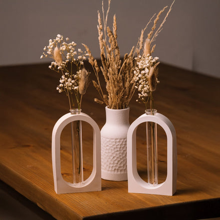 herzton Vasen-Halter zwei weiße Raysin-Bögen mit Glasröhrchen und Trockenblumen auf Holztisch