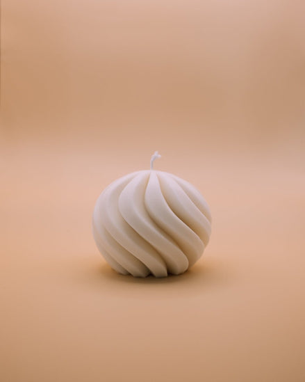 herzton Wave Sphere, cremeweiße Kugelkerze mit gedrehter Spiralstruktur, freistehend auf warmem Hintergrund